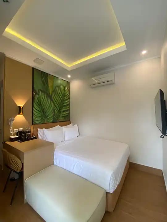 Bright deluxe room with botanical wall artwork and a compact writing desk